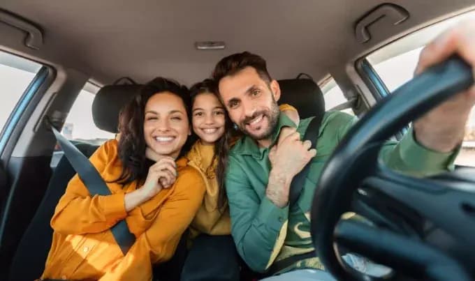 A family with husband, wife and daughter similing and facing forward in camera
