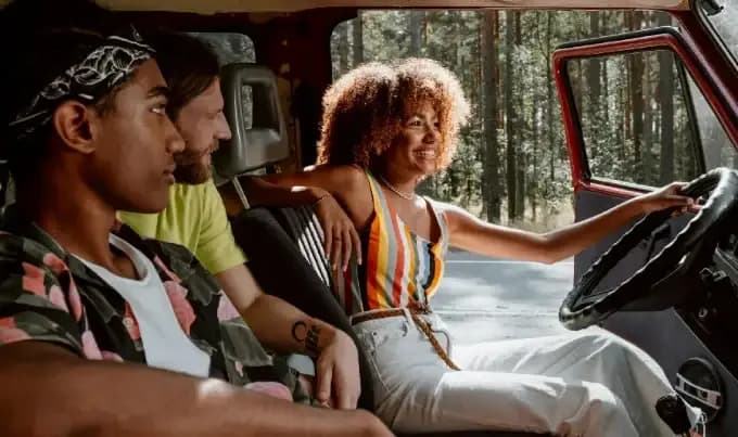 A group of 3 friends smiling and looking forward in a car